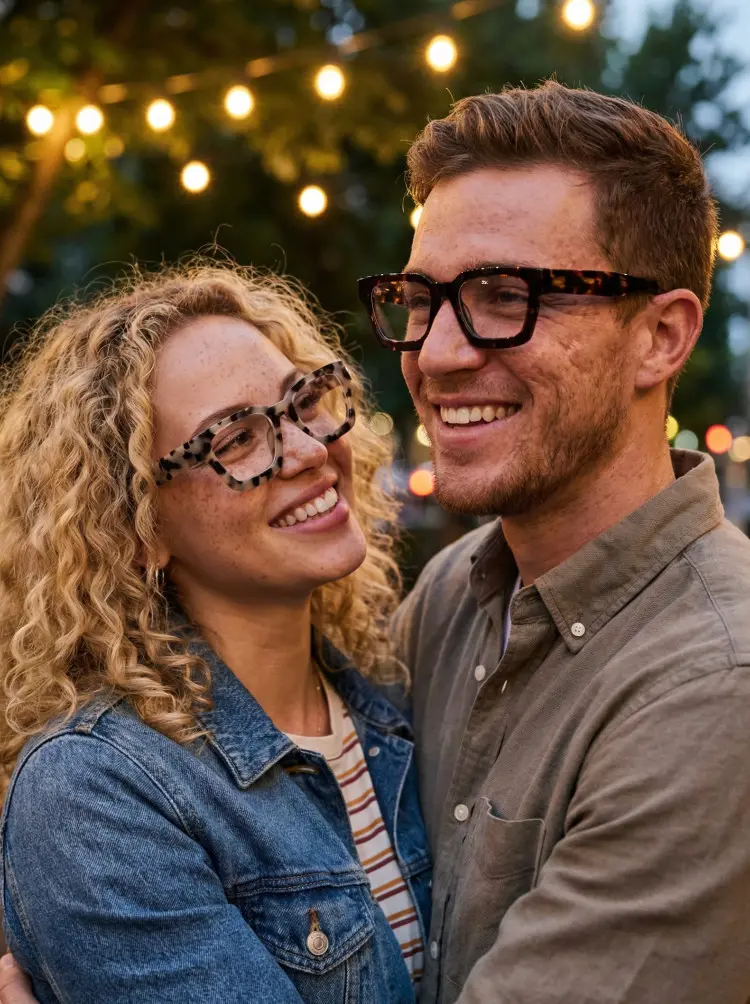 Couple models wearing everyday brown tortoise rectangle acetate eyeglasses in an outdoor setting with string lights. SPU: SA0552302