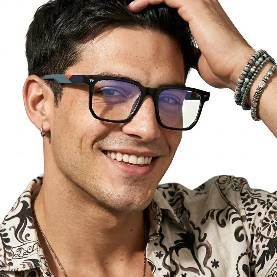Three-quarter view of male wearing black square eyeglasses, hand in hair, smiling, SR0032604