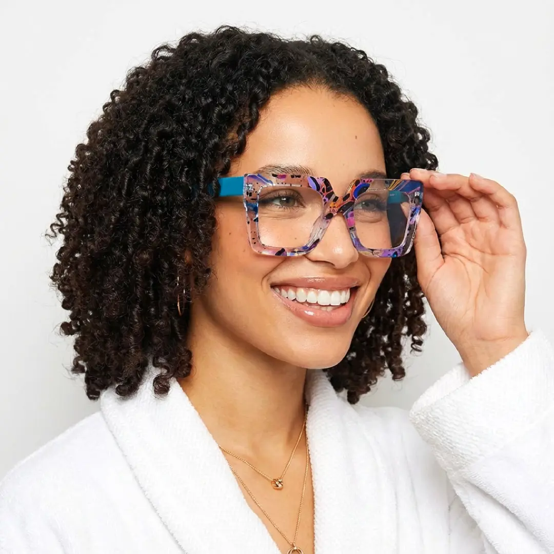 Looking away view of female wearing multicolor square eyeglasses, holding glasses, friendly smile, SR0082509