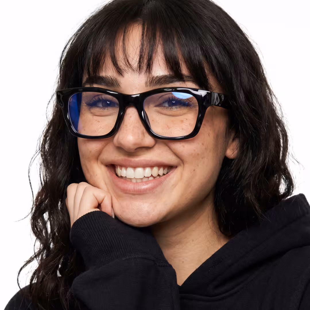Female wearing black square tr90 eyeglasses, smiling while resting chin on hand. SPU: SR0122605