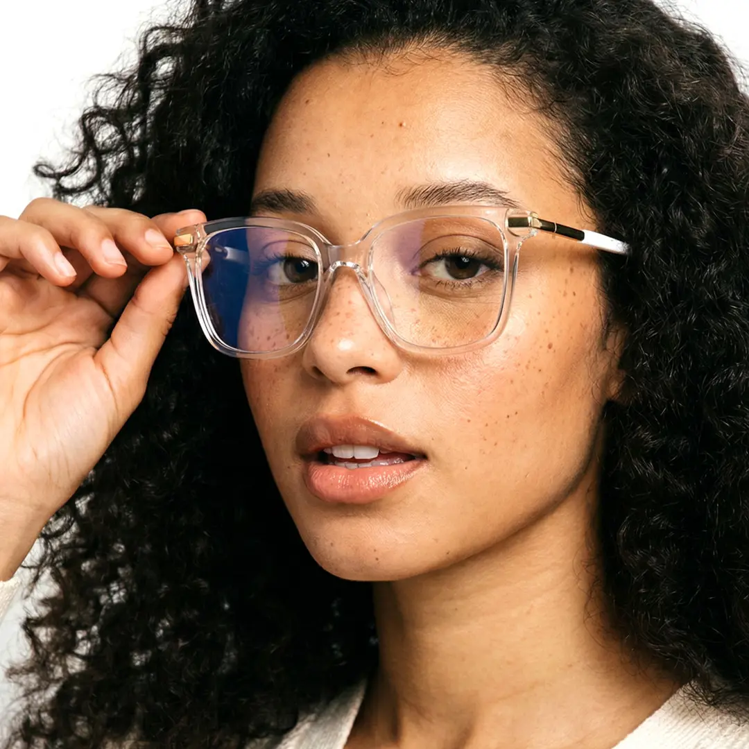 Three-quarter view of female wearing clear square eyeglasses, holding glasses, natural expression, SR0192502