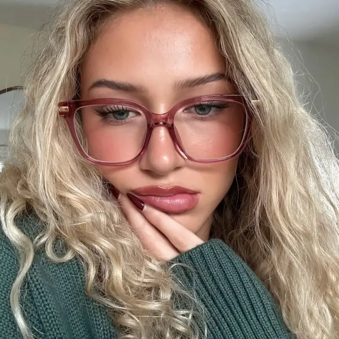 Front view of female wearing pink square eyeglasses, resting chin on hand, relaxed expression, SR0192502