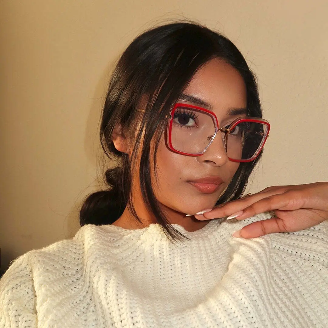 Three-quarter view of female wearing red square eyeglasses, resting chin on hand, neutral expression, SR0332503
