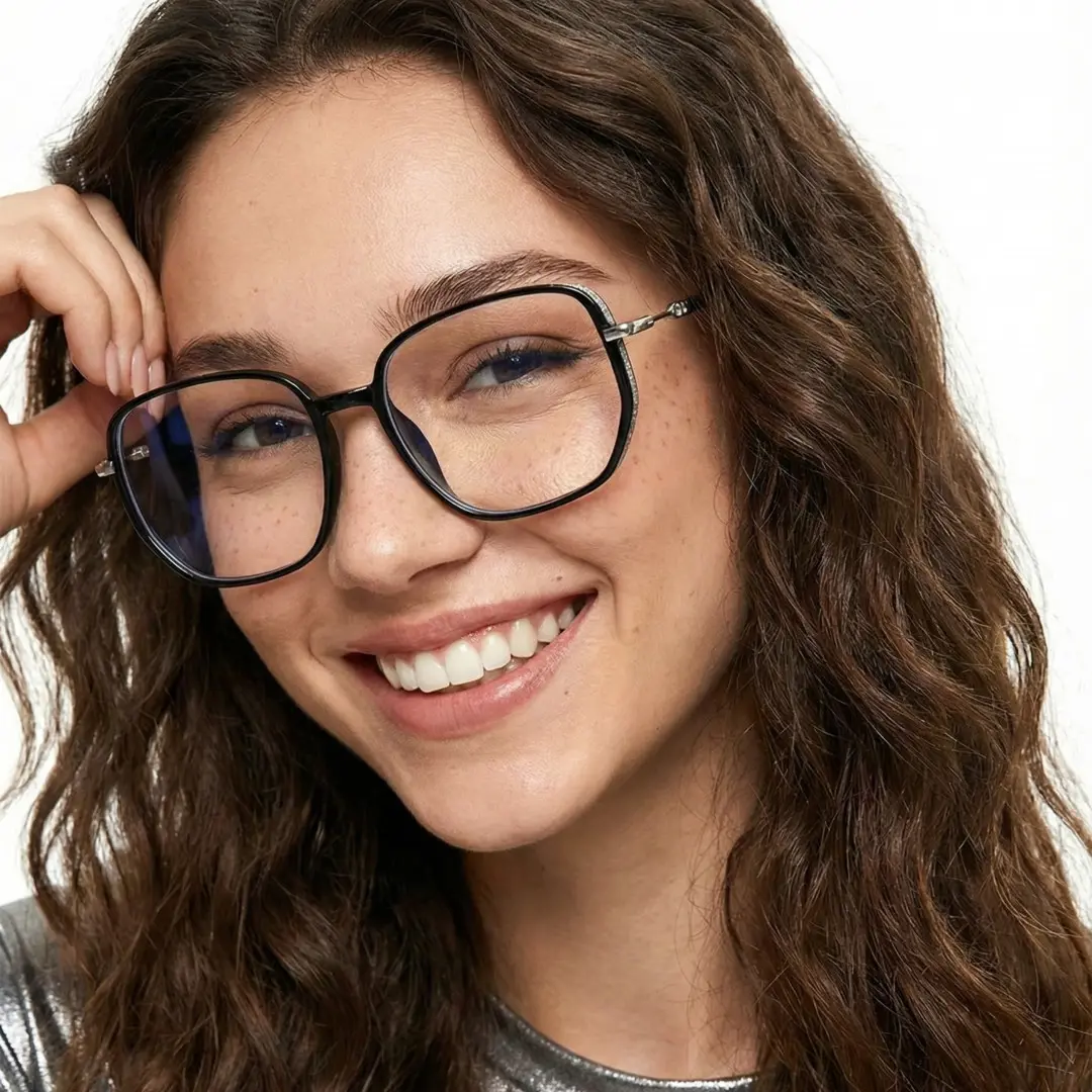Tilted head view of female wearing vintage black square eyeglasses, touching frame, smiling, SR0992509