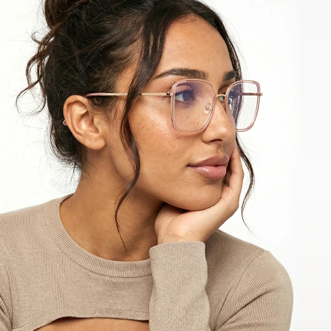 Three-quarter view of female wearing pink square eyeglasses, resting chin on hand, friendly smile, SX0302508