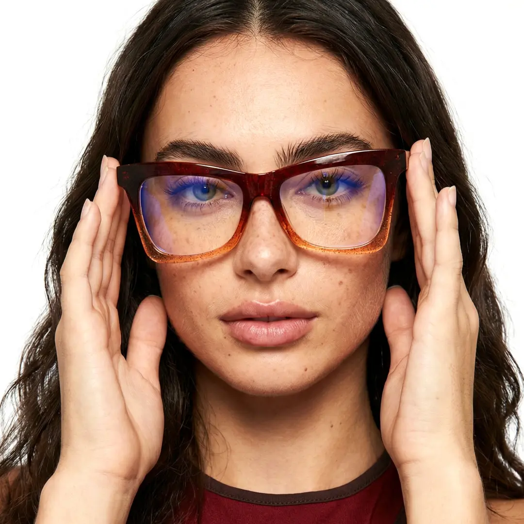 Front view of female wearing brown butterfly eyeglasses, holding glasses, natural expression, UR0152502