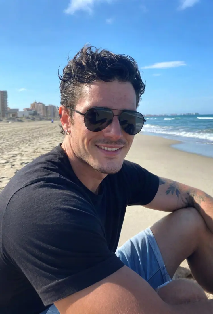 Male model wearing vintage black aviator metal sunglasses at a sunny beach. SPU: AM004260
