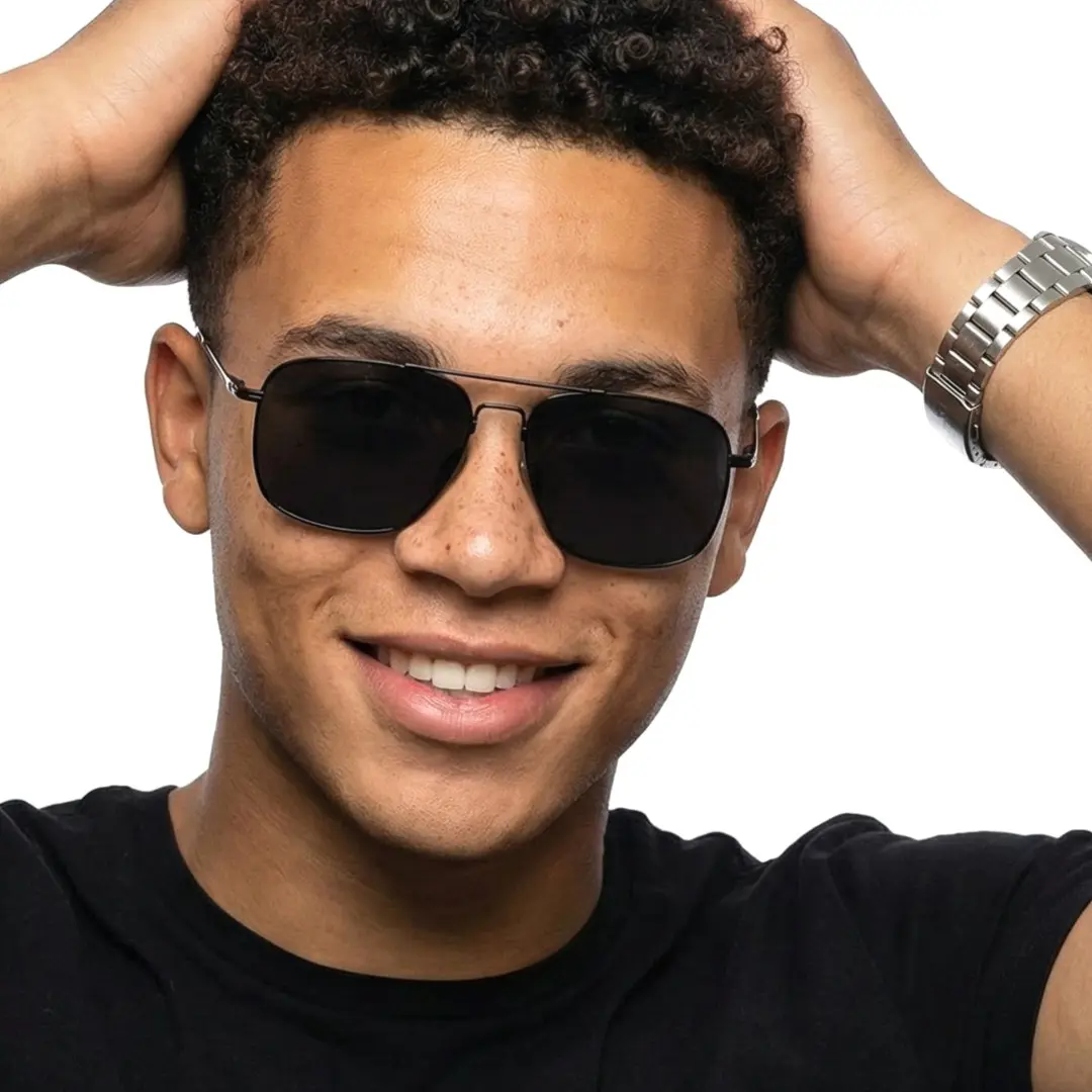 Three-quarter view of male wearing black aviator sunglasses, hand in hair, friendly smile, AM0052603