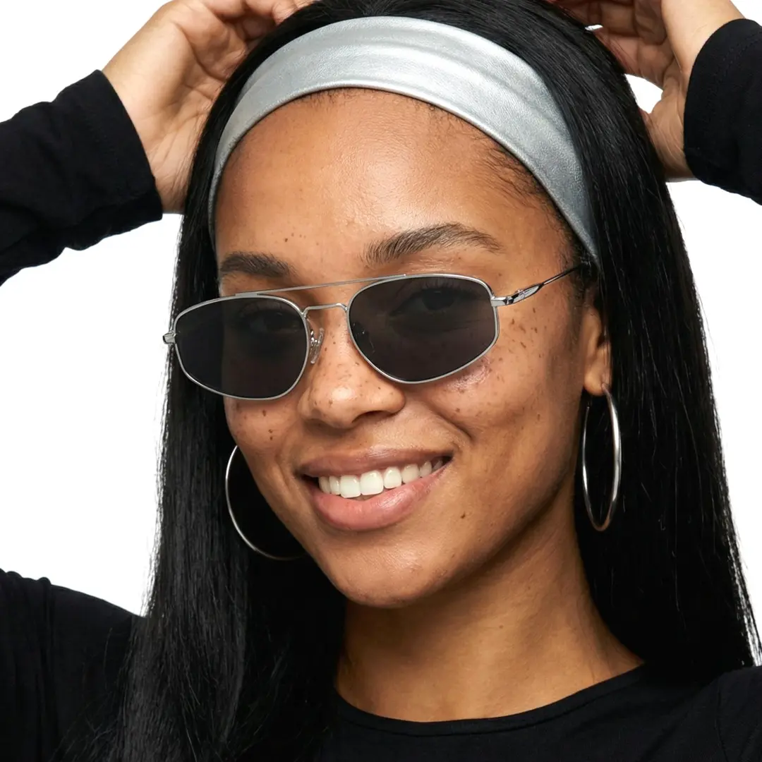 Three-quarter view of female wearing fashion silver aviator sunglasses, hand in hair, smiling, AM0082603