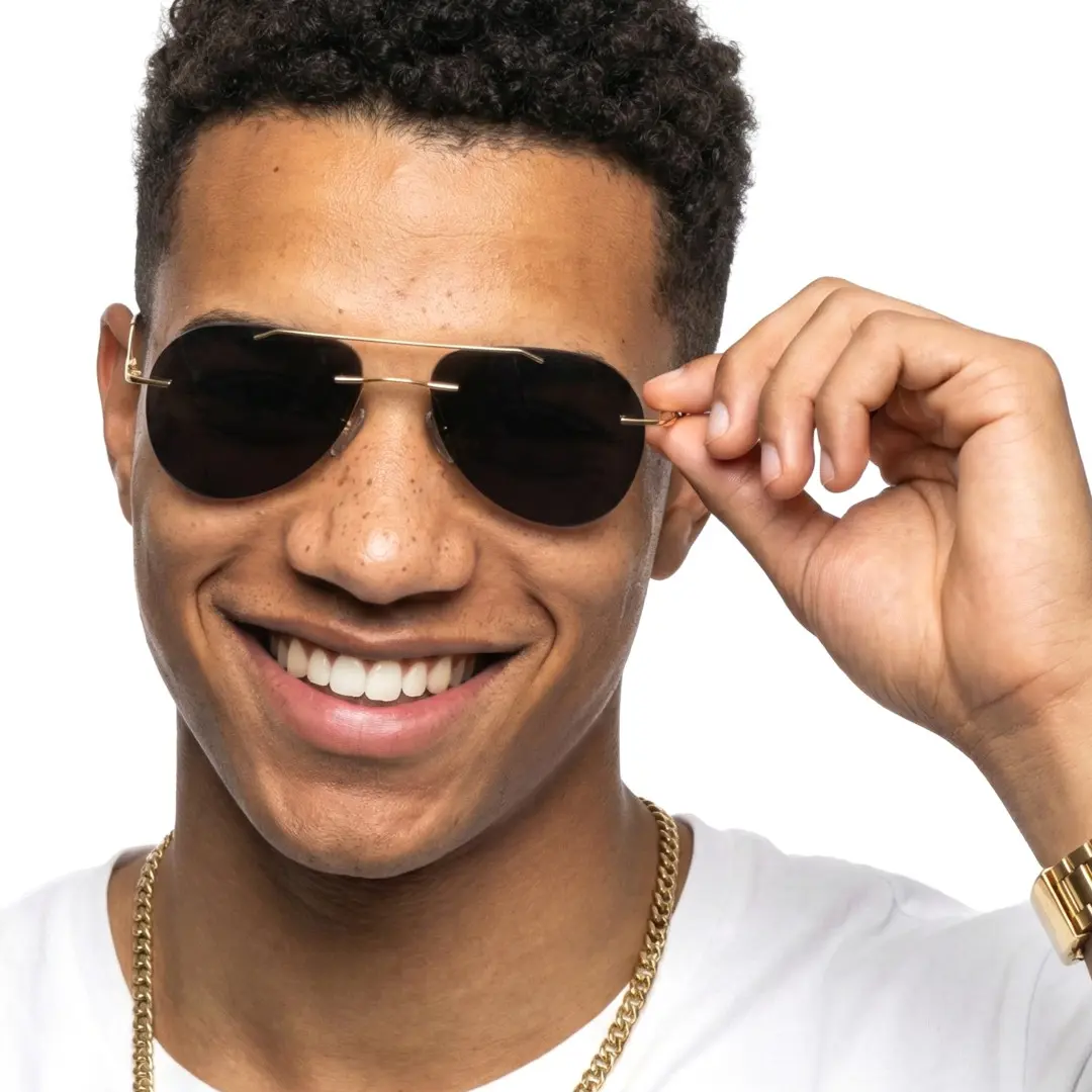 Front view of male wearing gold aviator sunglasses, holding glasses, smiling, AM0492506S