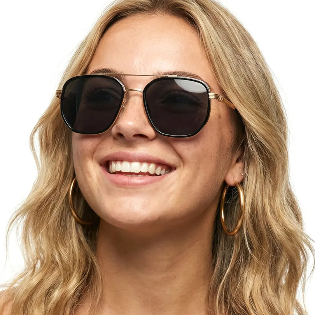 Tilted head view of female wearing gold aviator sunglasses, friendly smile, AM0622505