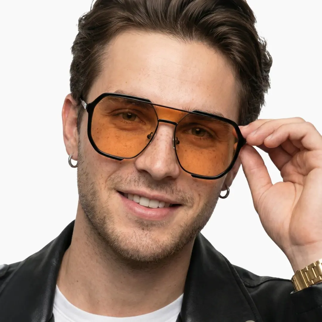 Front view of fashion male wearing orange aviator sunglasses, holding glasses, natural smile, AR0042410
