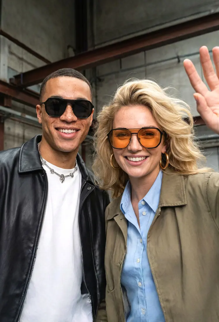 Couple models wearing fashion black and orange aviator tr90 sunglasses in an urban industrial setting. SPU: AR0042410.