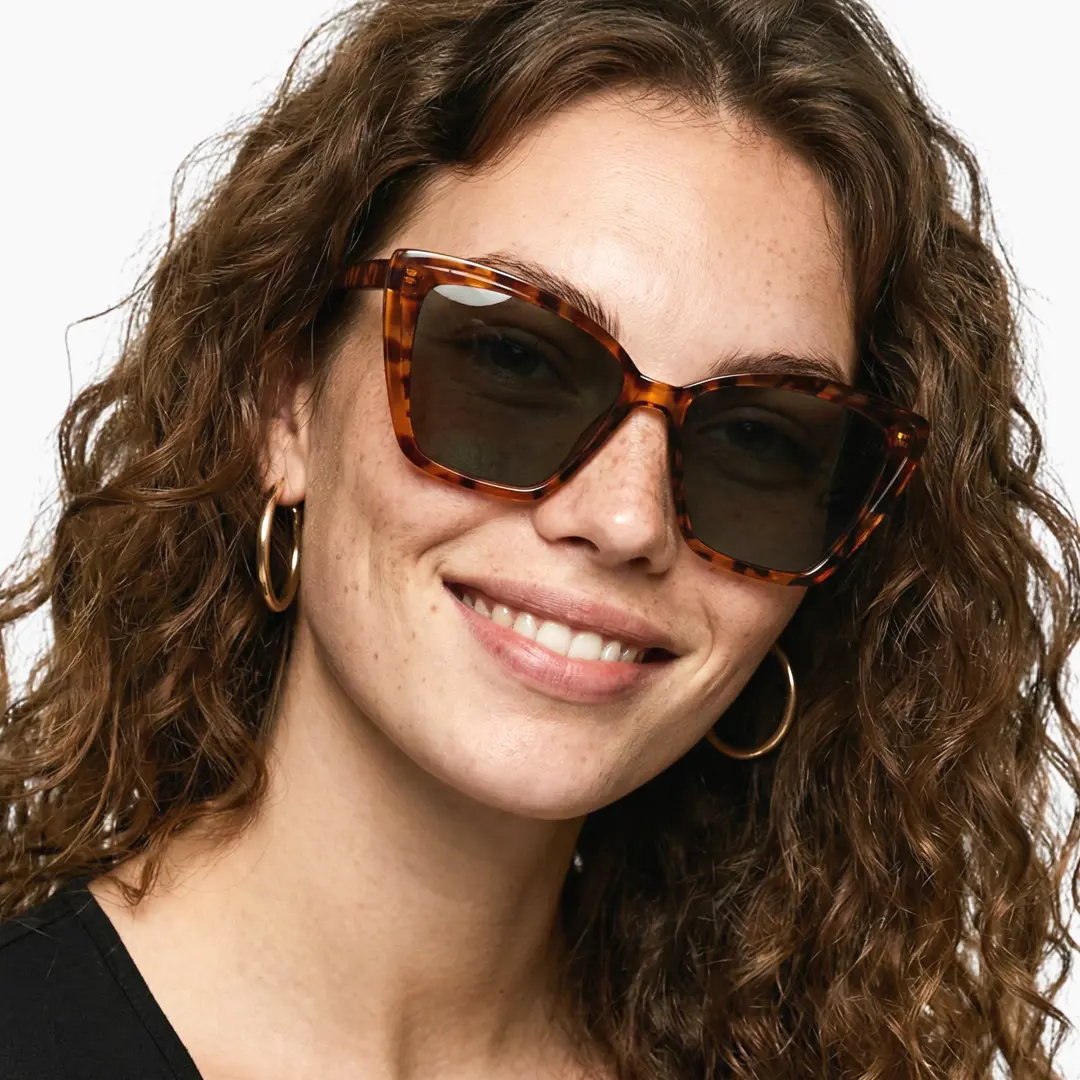 Front view of female wearing tortoise cat eye sunglasses, smiling, CP0102506