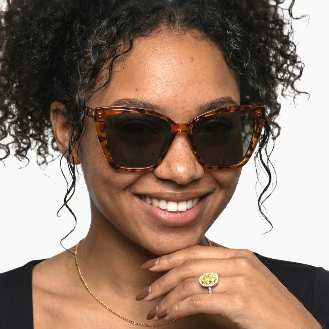 Front view of female wearing tortoise cat eye sunglasses, resting chin on hand, natural smile, CP0102506