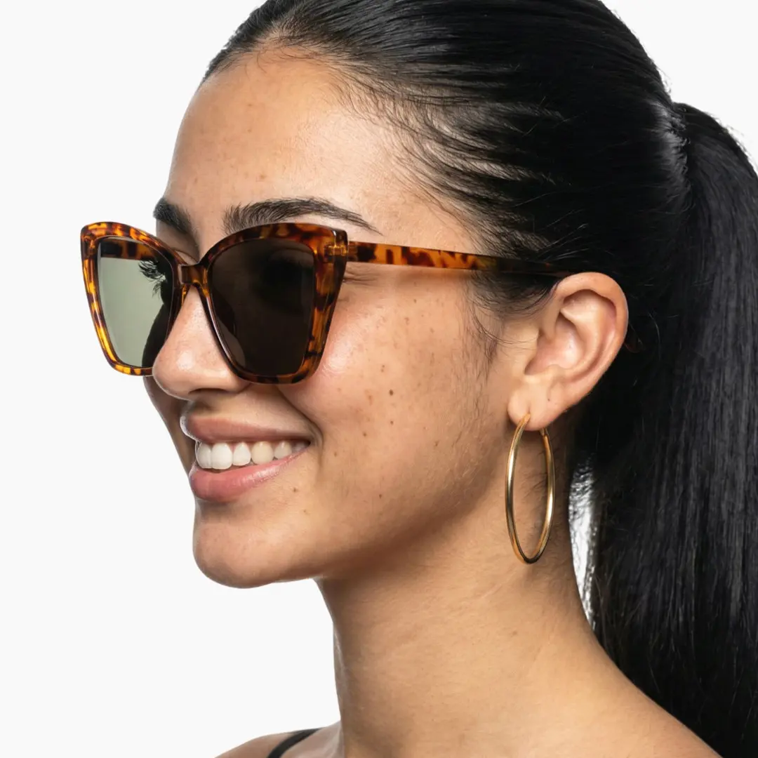 Three-quarter view of female wearing tortoise cat eye sunglasses, smiling, CP0102506