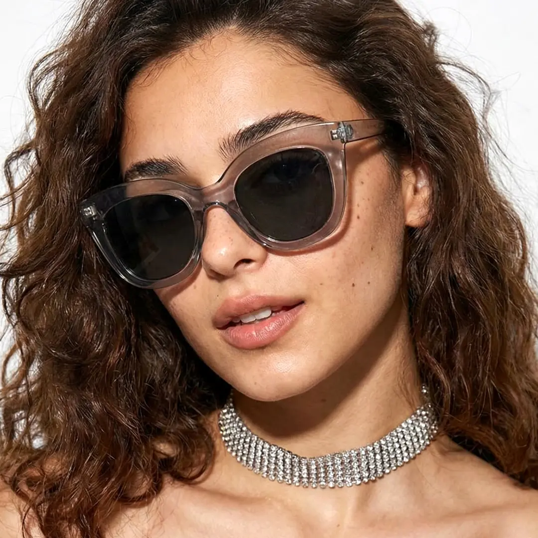 Front view of female wearing grey cat eye sunglasses, tilting head, natural expression, CR0172404