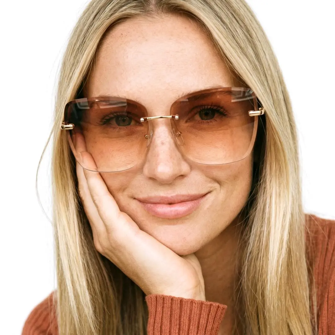 Front view of female wearing beige cat eye sunglasses, resting chin on hand, natural smile, CX0102505