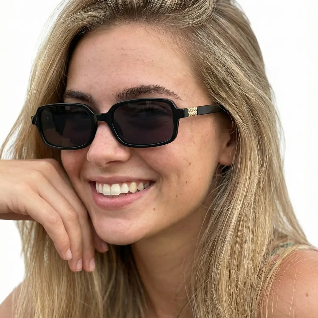Profile view of female wearing black rectangle sunglasses, resting chin on hand, friendly smile, EP0172507