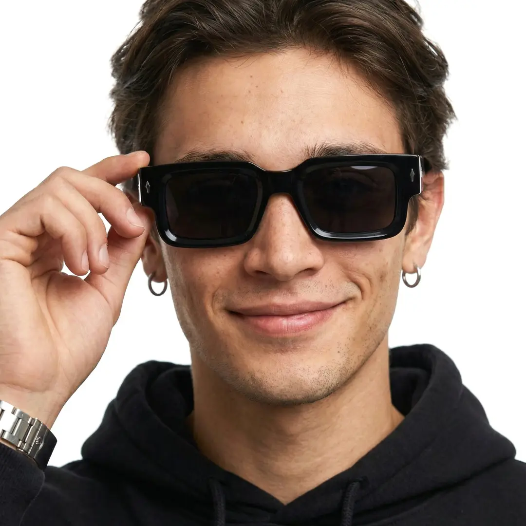 Front view of male wearing black rectangle sunglasses, holding glasses, smiling, EP0542509S