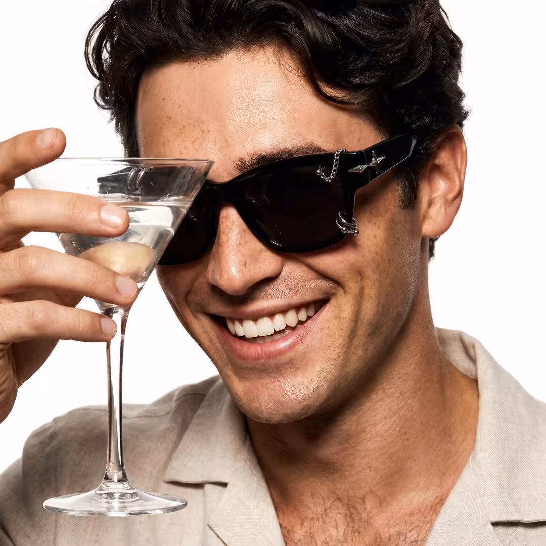 Three-quarter view of male wearing silver rectangle sunglasses, hand holding a wine glass, smiling, ER0072604