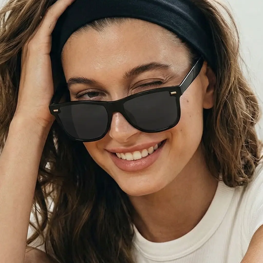 Close-up view of female wearing black rectangle sunglasses, hand resting on forehead, smiling, ER0122604