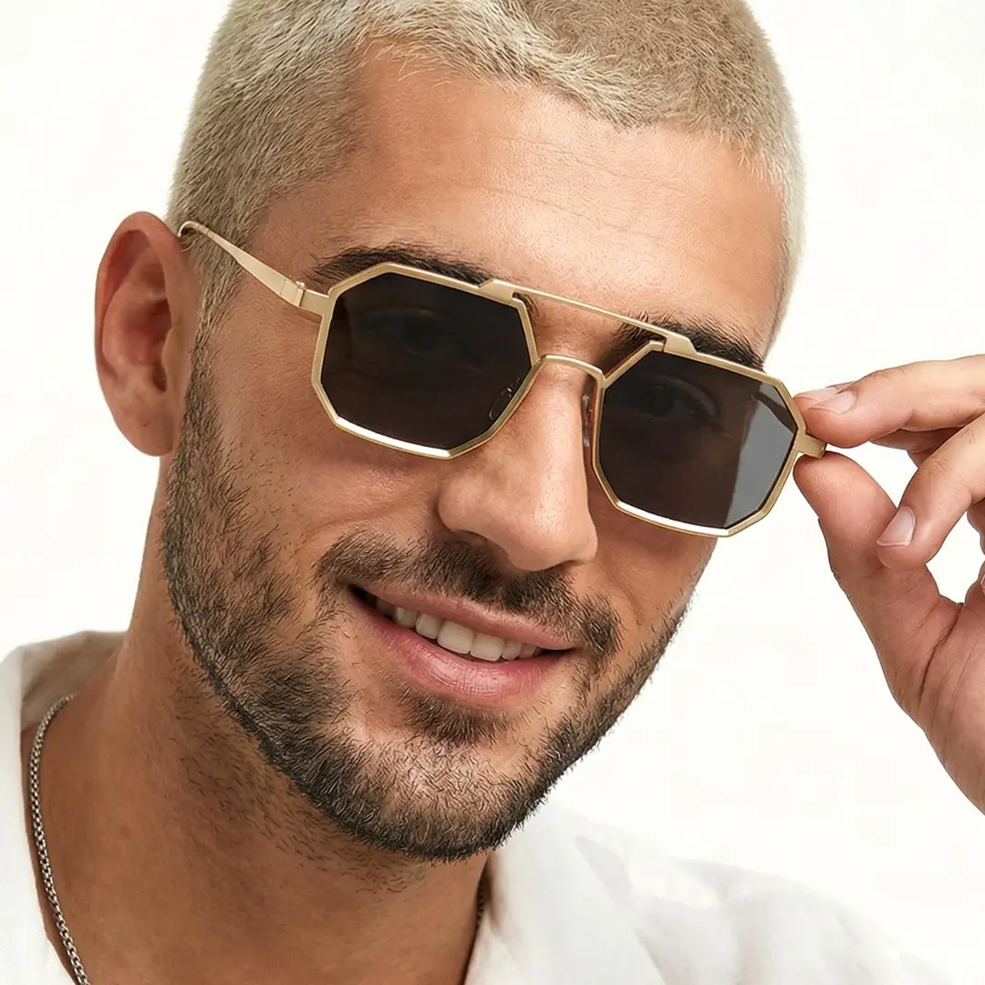 Front view of male wearing steampunk grey geometric sunglasses, holding glasses, natural smile, GM0012505