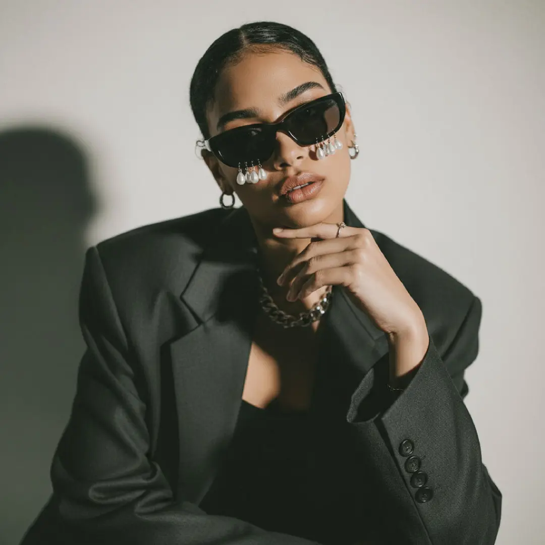 Front view of female wearing fashion black oval sunglasses, resting chin on hand, confident expression, OL0102506