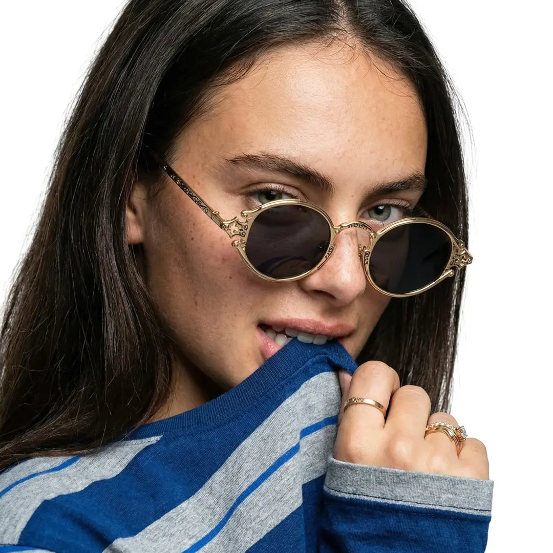 Three-quarter view of female wearing fashion gold oval sunglasses, relaxed expression, OM0352601