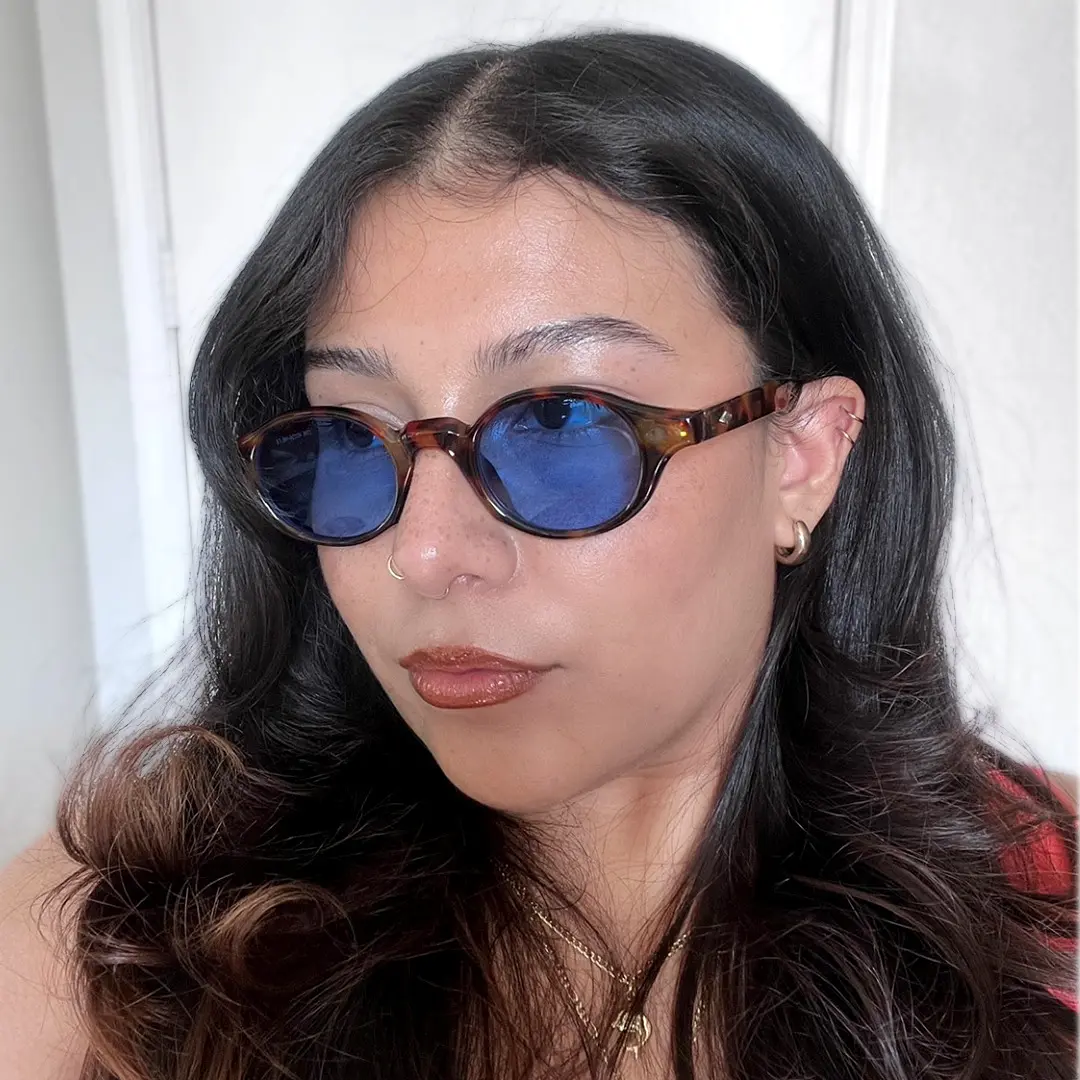 Profile view of female wearing tortoise oval sunglasses, neutral expression, OP0062505