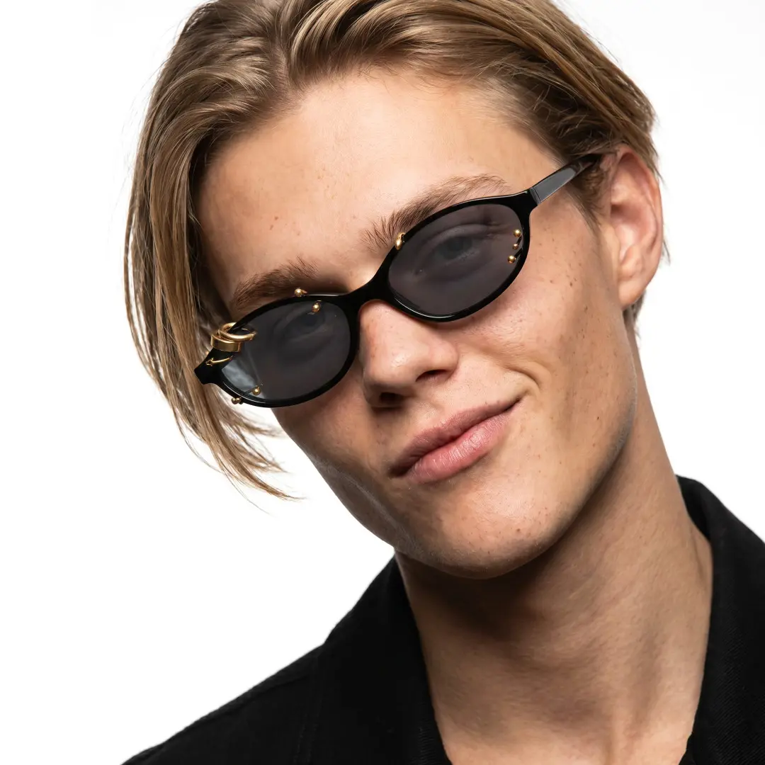 Tilted head view of male wearing gold oval handcrafted polarized sunglasses, smiling, OP0092604