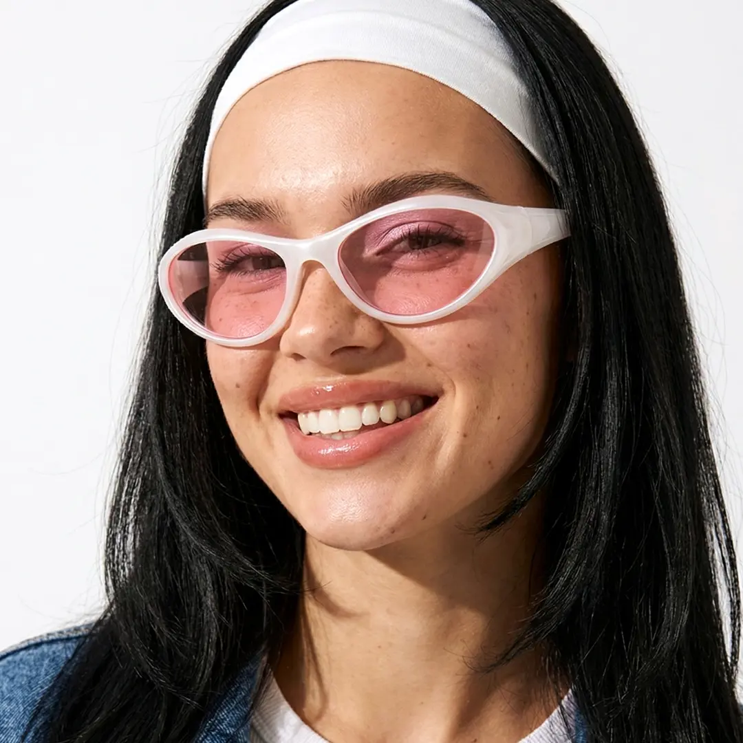 Three-quarter view of female wearing pink oval sunglasses, smiling, OP0182603