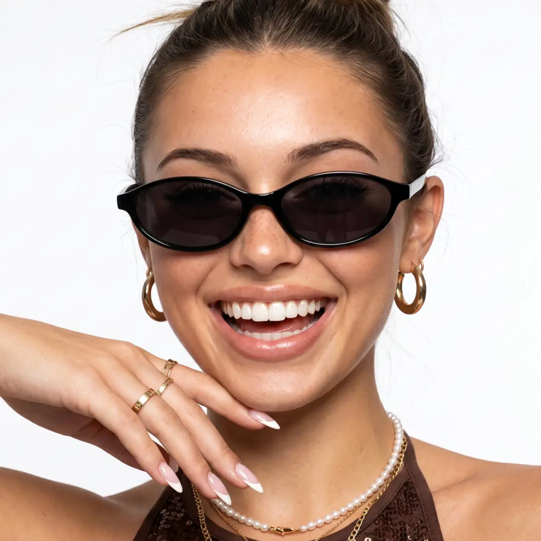 Looking straight ahead view of female wearing black oval sunglasses, hand resting on chin, big smile, OP0272603