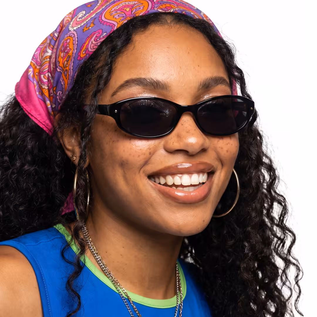 Three-quarter view of female wearing y2k black oval sunglasses, smiling, OP0332604
