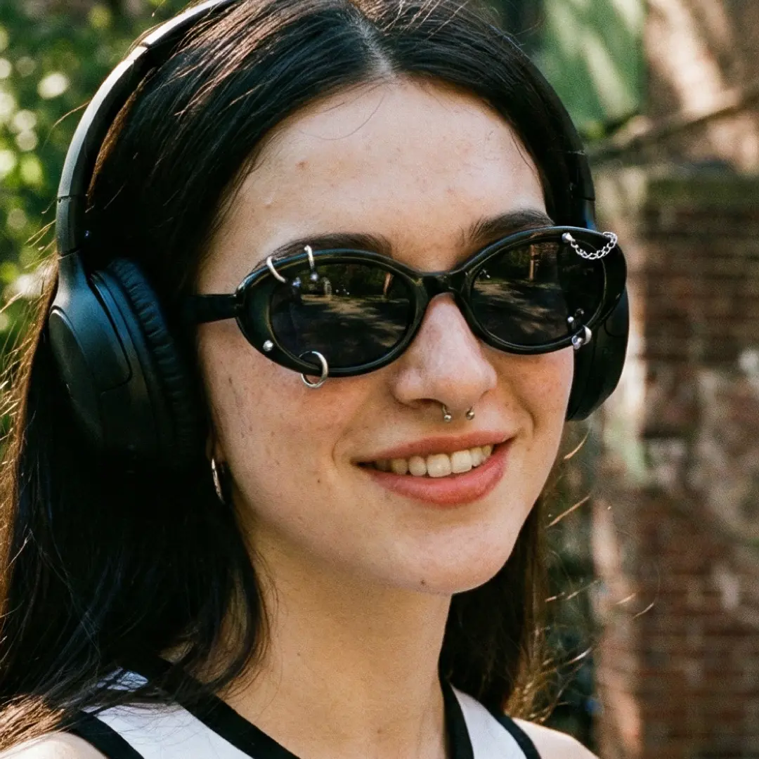 Looking away view of female wearing black oval handcrafted polarized sunglasses, smiling, OR0022509