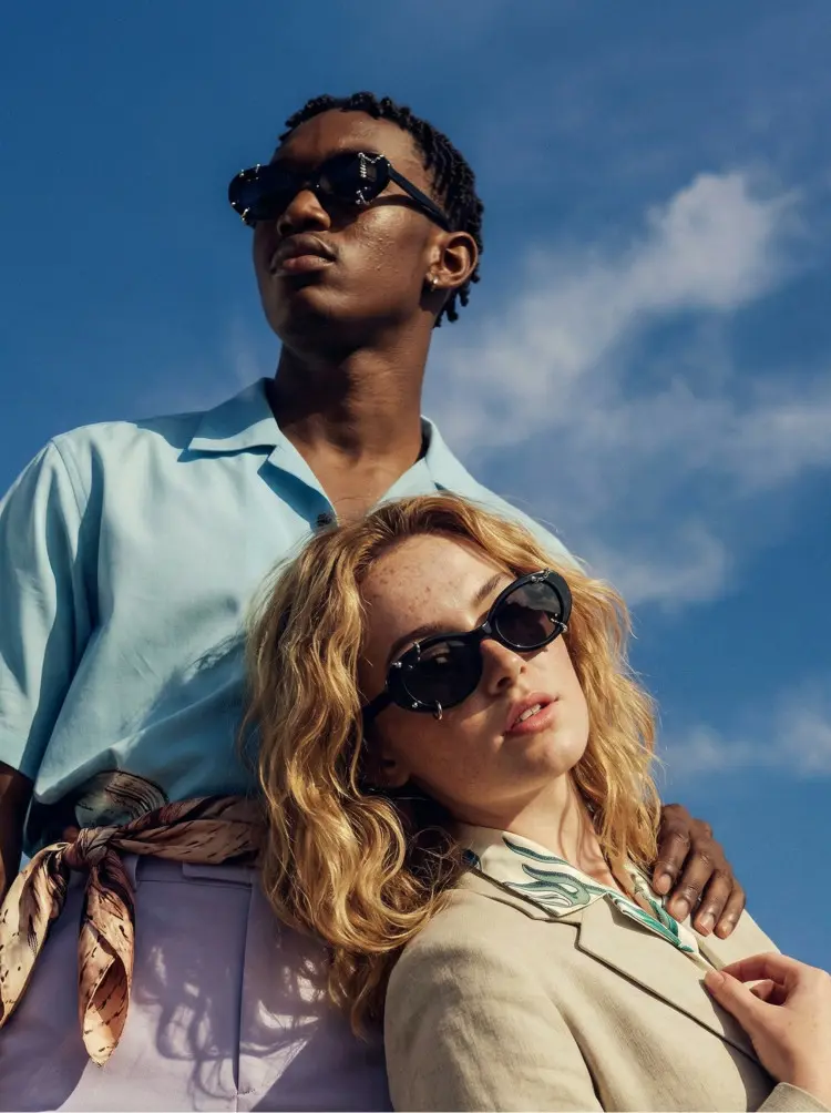 Couple model wearing handcrafted black oval tr90 handcrafted polarized sunglasses under a bright blue sky outdoors. SPU: OR0022509