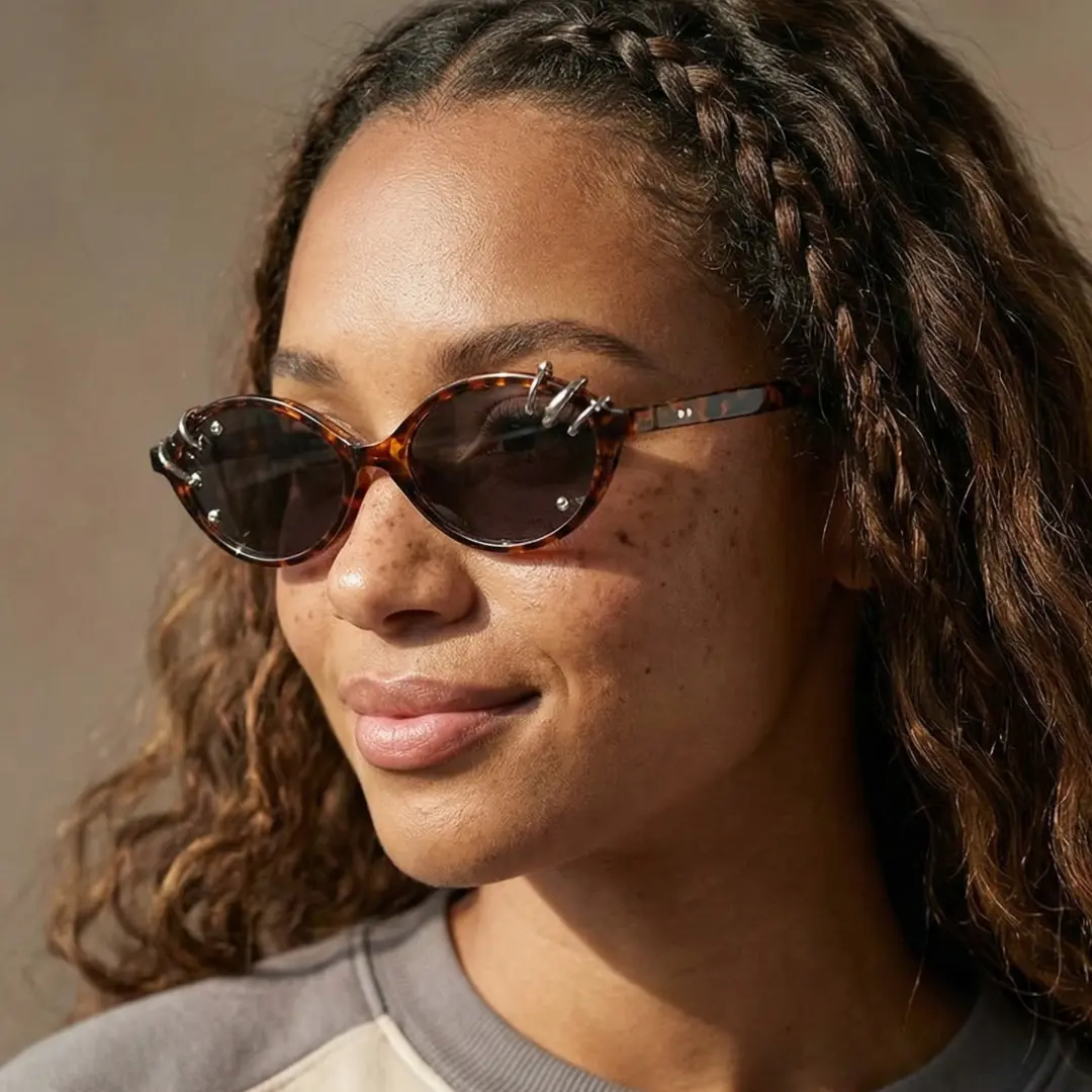 Looking away view of female wearing tortoise oval handcrafted polarized sunglasses, friendly smile, OR0042509