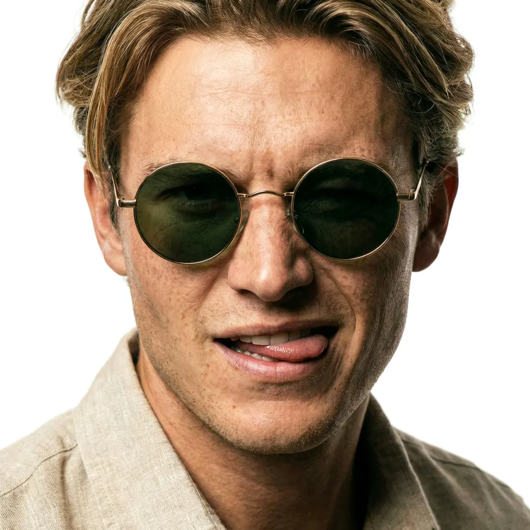 Front view of male wearing army green round sunglasses, sticking out tongue, RM0012207