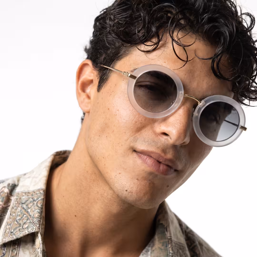 Front view of male wearing vintage gold round sunglasses, tilting head, soft smile, RM0012605
