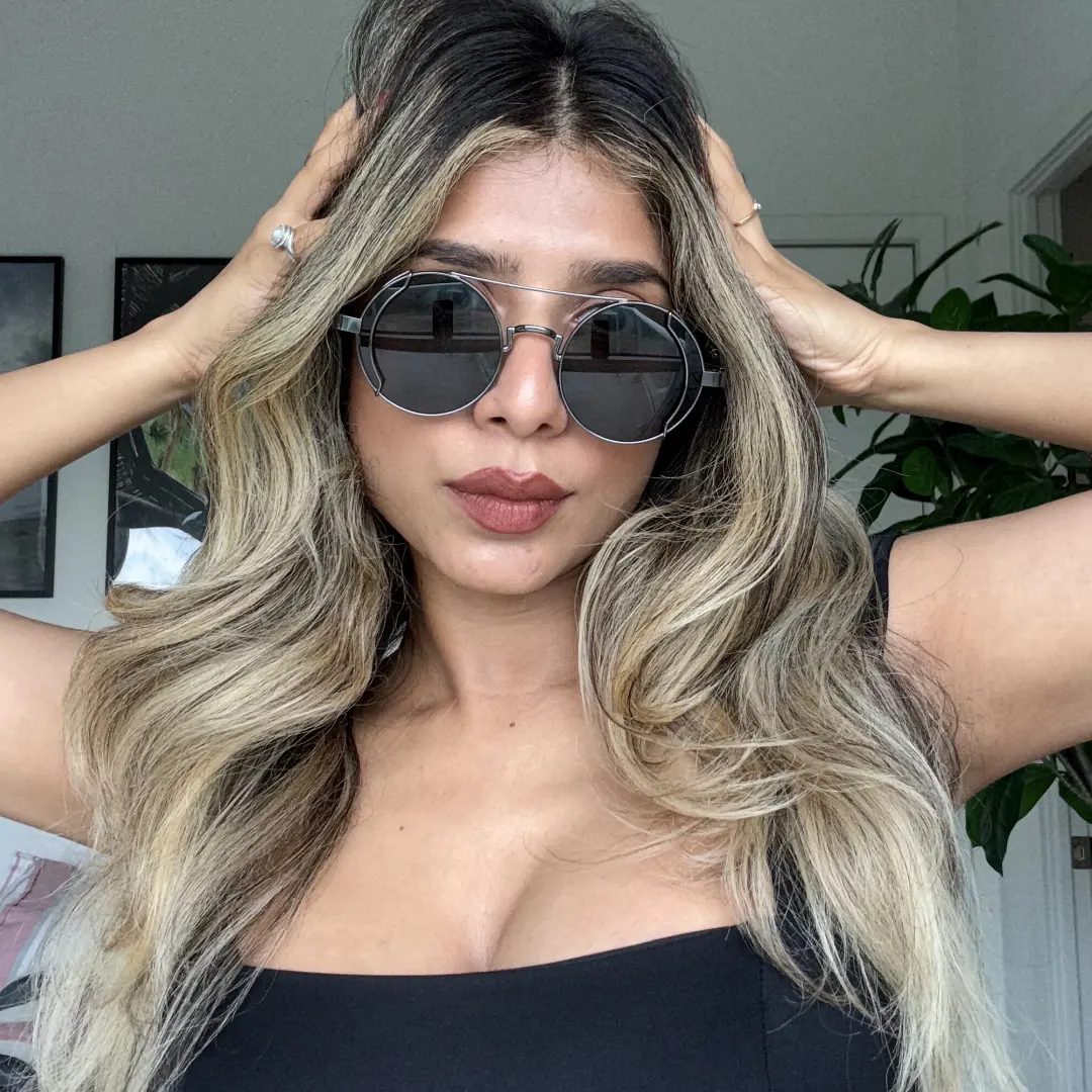 Front view of female wearing steampunk black round sunglasses, hand in hair, neutral expression, RM0102303