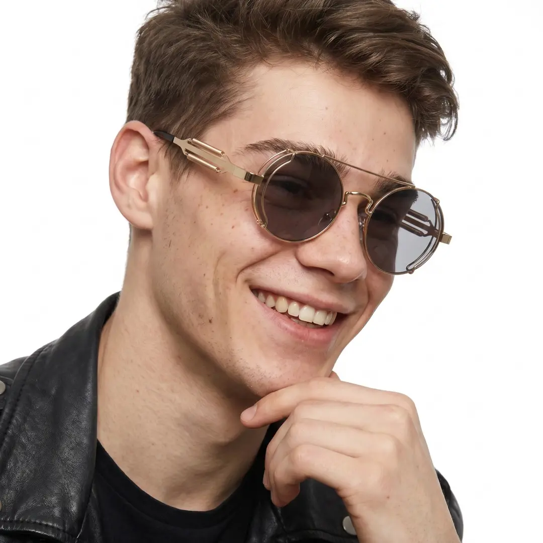 Three-quarter view of male wearing steampunk gold round sunglasses, resting chin on hand, smiling, RM0102303