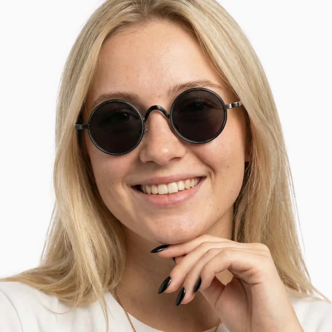 Front view of female wearing black round sunglasses, resting chin on hand, natural smile, RM0162506