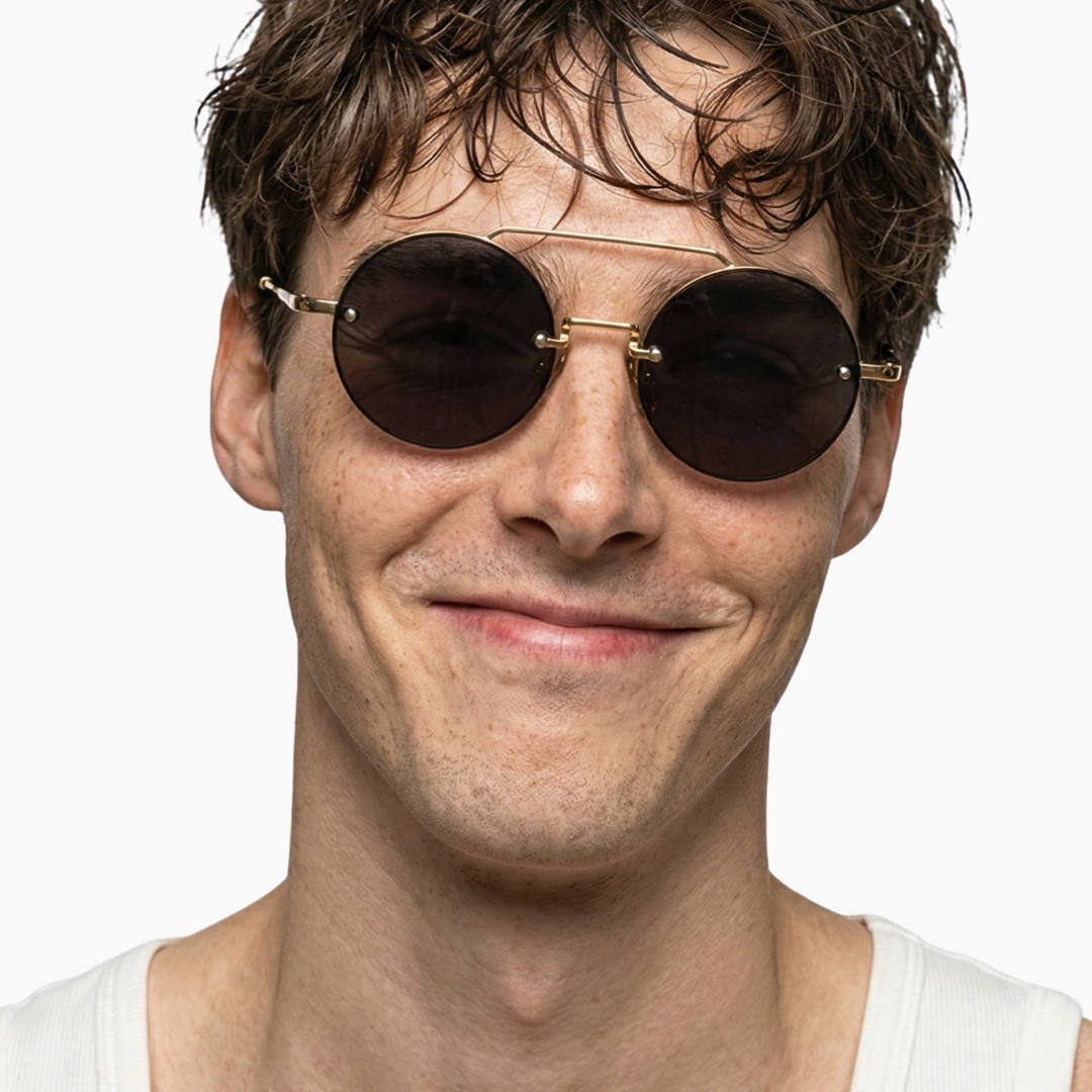 Profile view of male wearing vintage gold round sunglasses, smiling, RM0252507