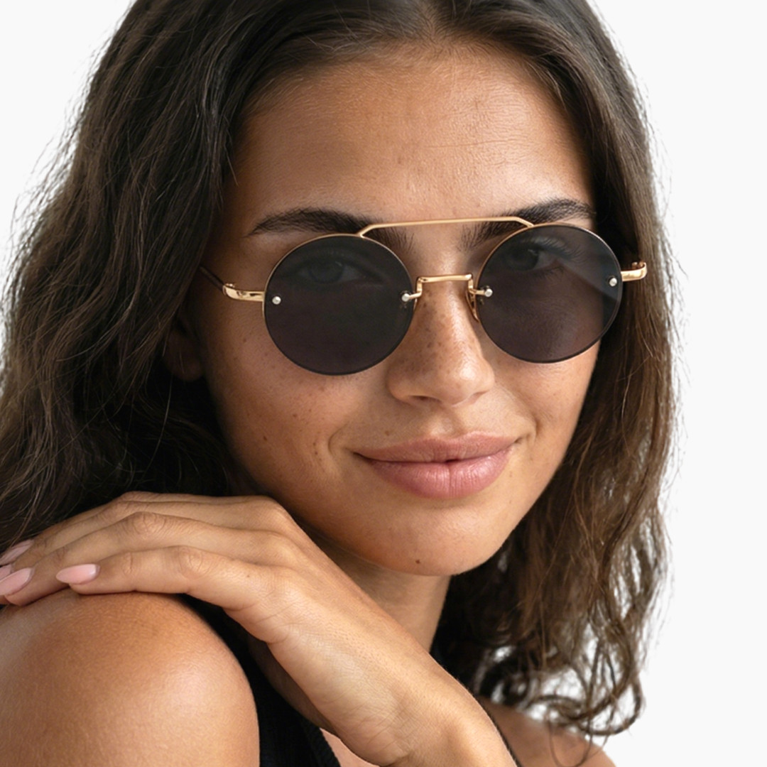 Over-the-shoulder view of female wearing vintage gold round sunglasses, hand touching shoulder, natural smile, RM0252507