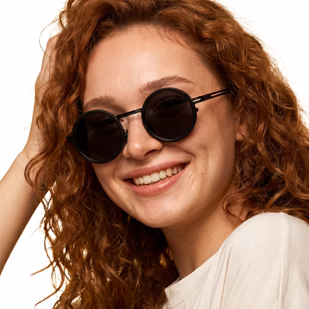 Female wearing steampunk black round metal sunglasses, smiling while hand resting on forehead. SPU: RM0292604