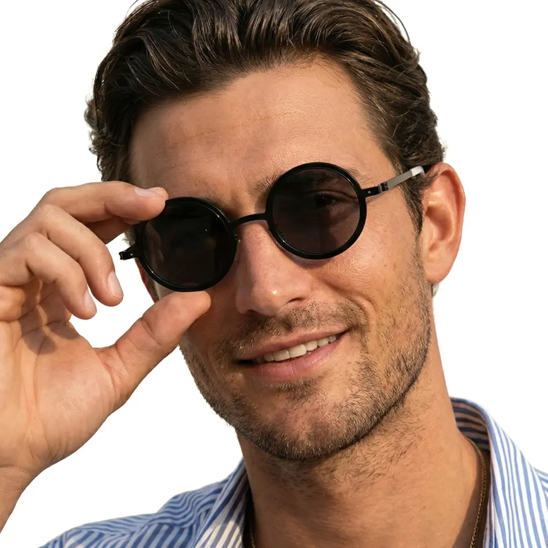 Front view of male wearing black round ND filter sunglasses, touching frame, smiling, RM0322507