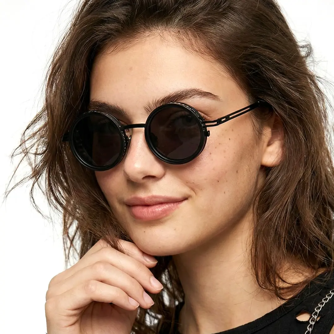 Profile view of female wearing steampunk black round sunglasses, hand in hair, soft smile, RM0352507