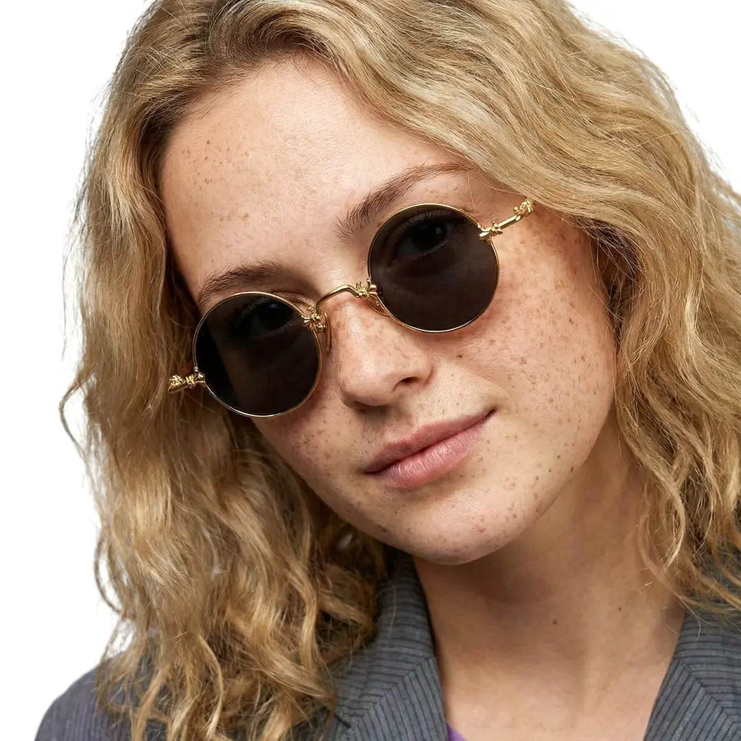 Tilted head view of female wearing gold round sunglasses, relaxed expression, RM0362505