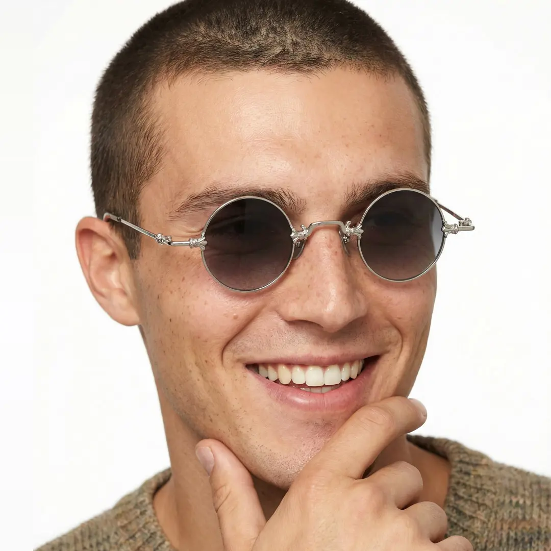 Slightly angled view of male wearing silver round sunglasses, resting chin on hand, big smile, RM0362505