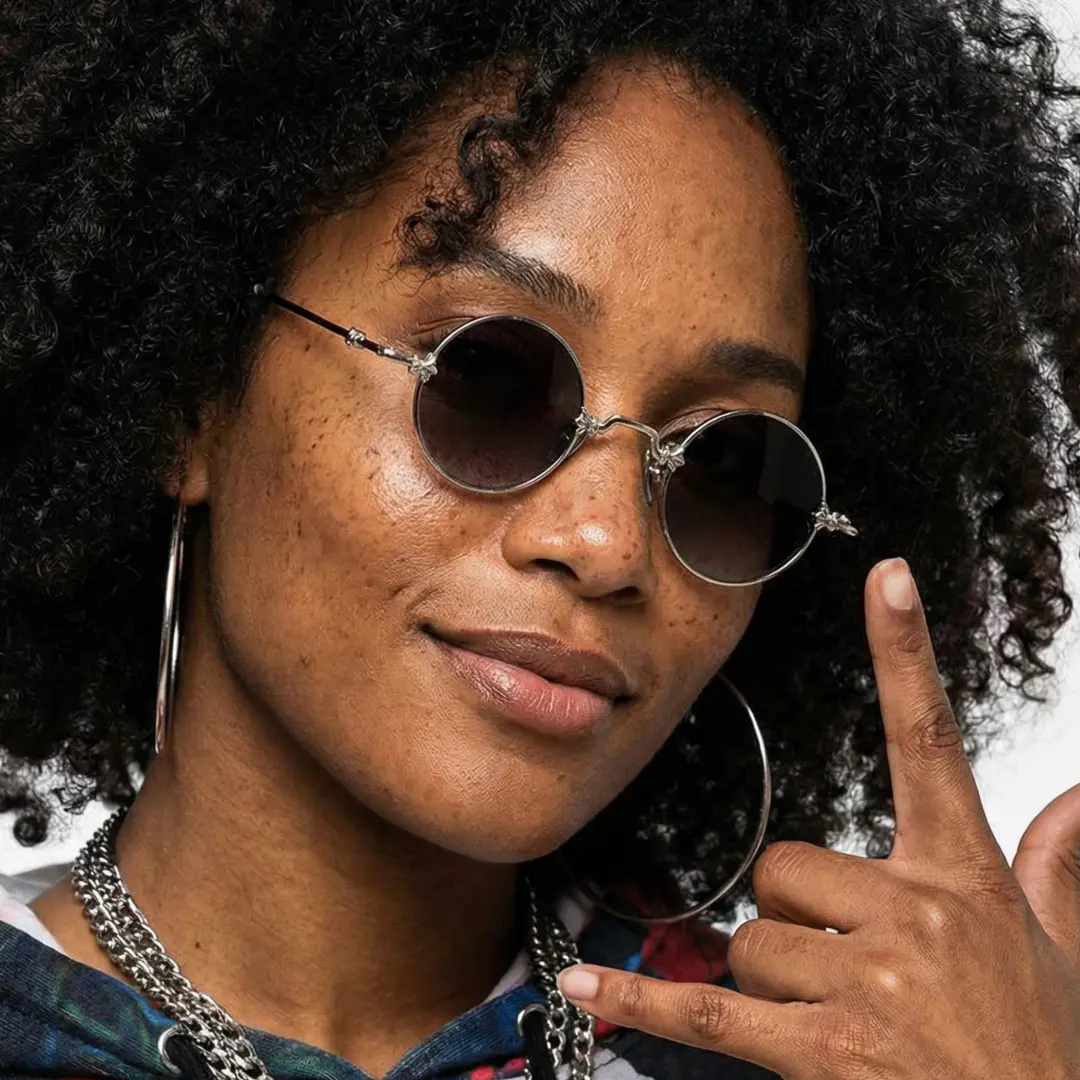 Three-quarter view of female wearing silver round sunglasses, hand near face, natural smile, RM0362505